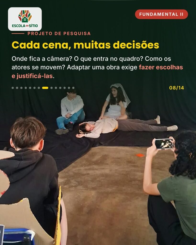Estudante grava com o celular uma cena com atores deitados no chão