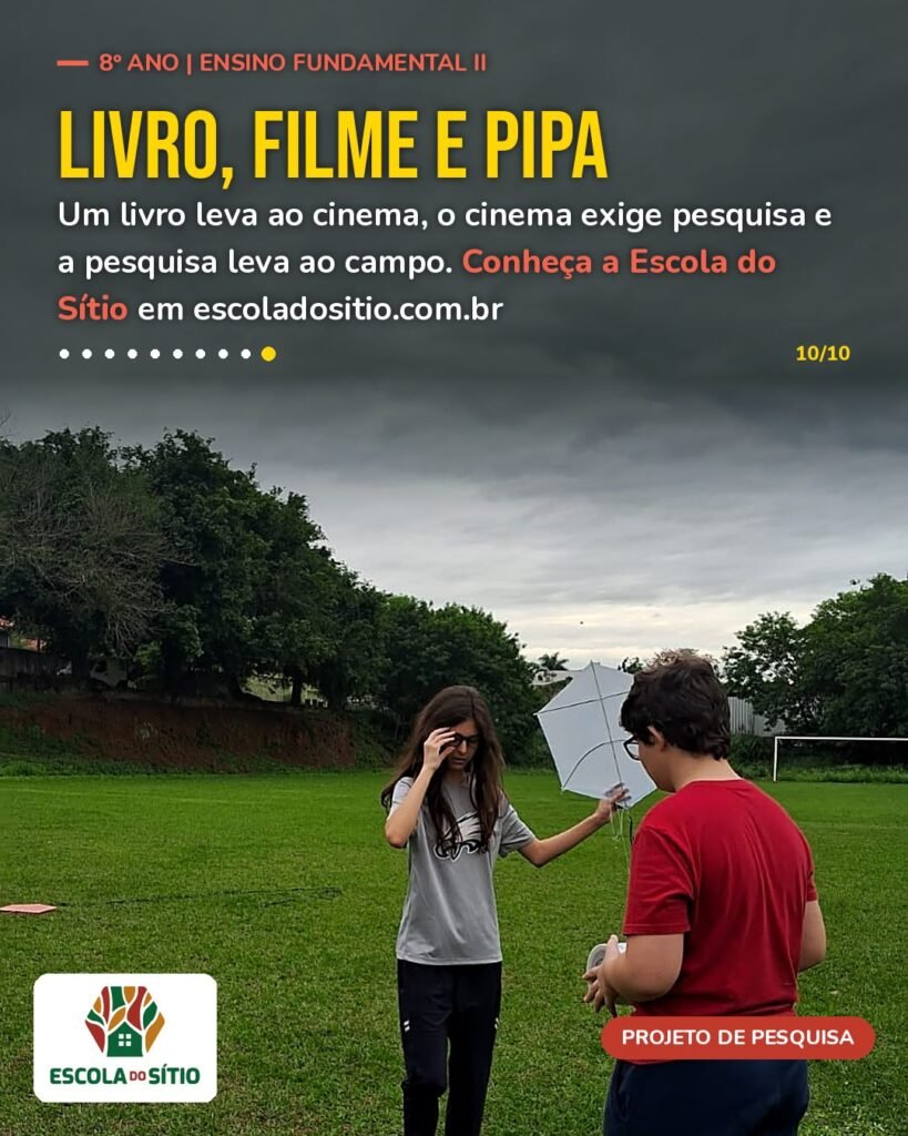 Dois estudantes do 8º ano com uma pipa branca no campo da Escola do Sítio