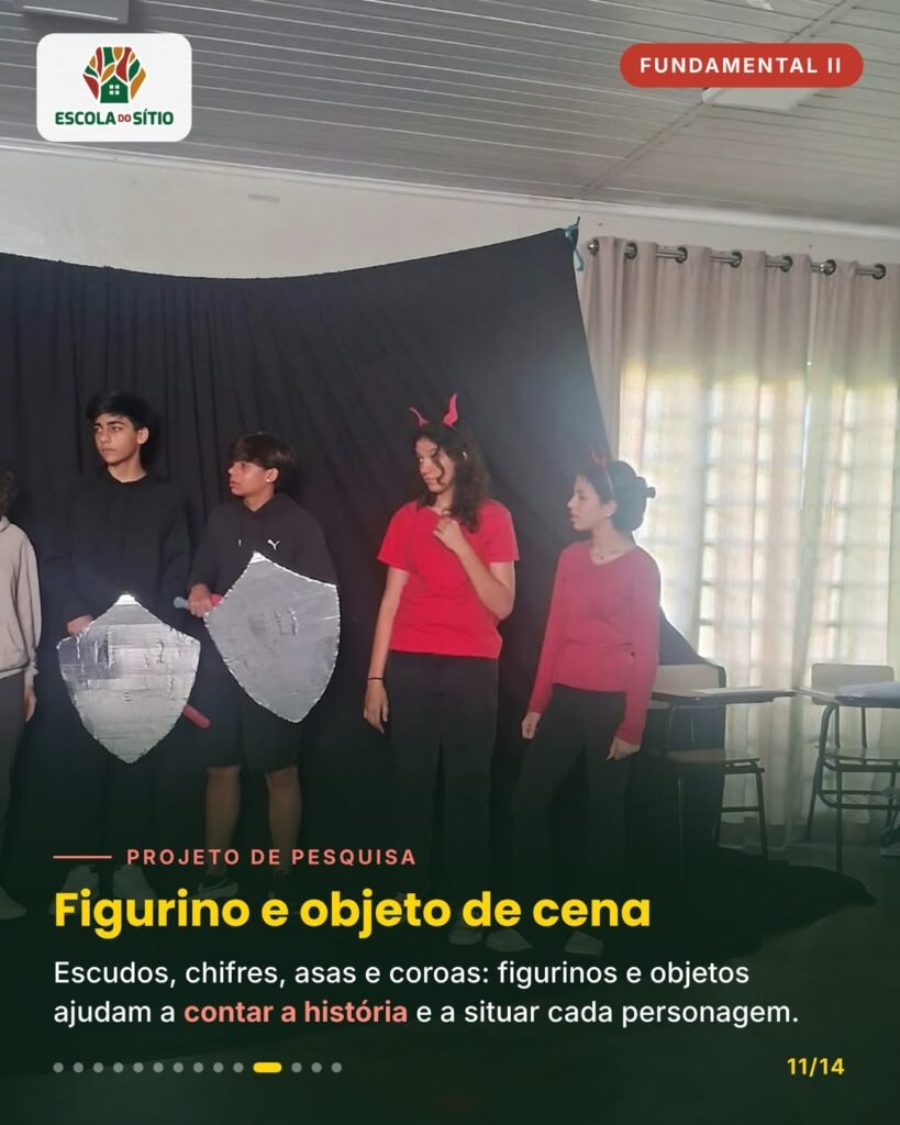 Estudantes com escudos de papelão e chifres vermelhos em frente ao pano preto